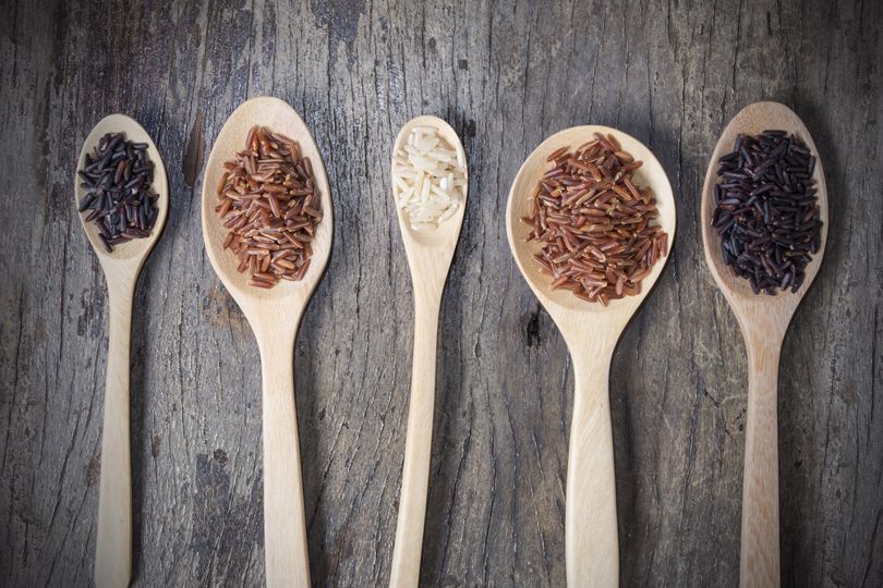 Wooden spoons filled with brown rice.